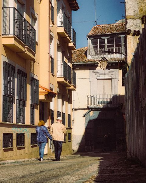 Two people walking away down a narrow Andalusian street